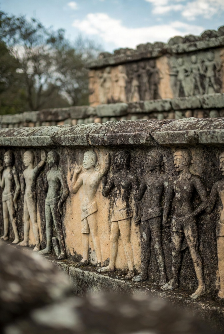 A weathered stone wall with ancient human figure carvings, set in a blurred natural landscape under soft lighting.