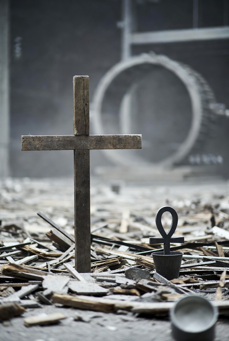 A photograph of a conceptual theological scene with a cross and resurrection symbol in an industrial setting.